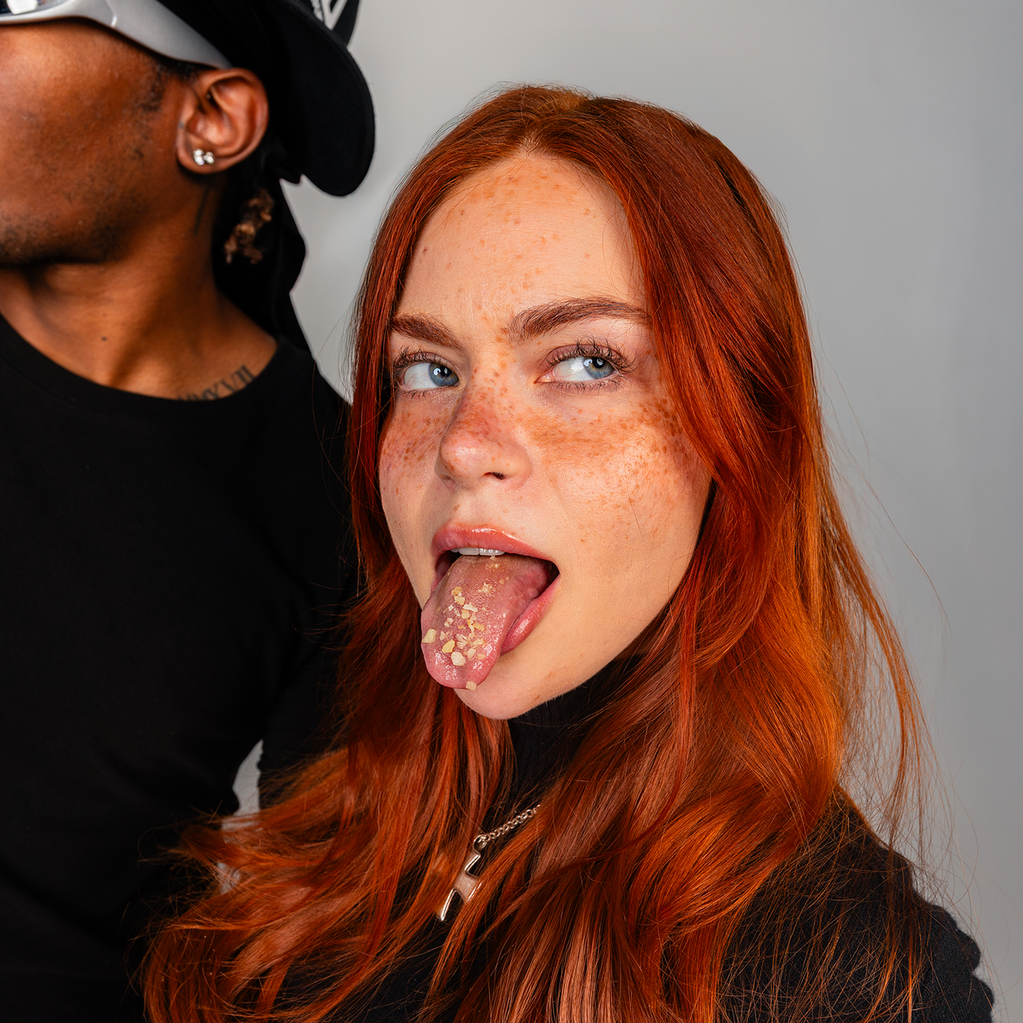 Person with red hair sticking out their tongue against a neutral background